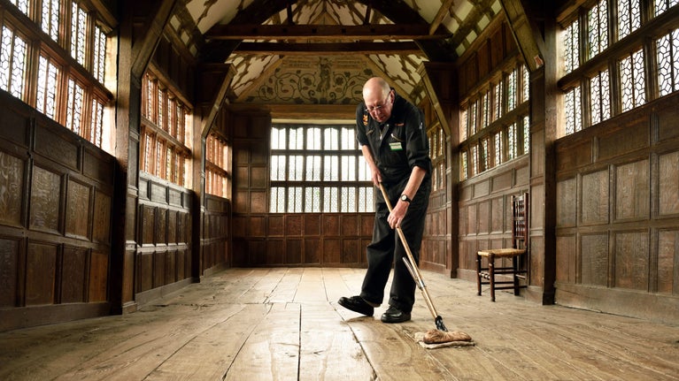 Volunteer sweeping the floor at Little Moreton Hall, Cheshire